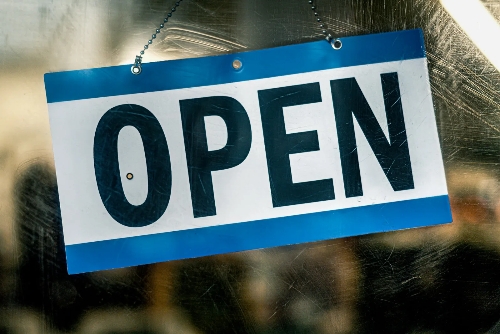 玻璃門上掛著一塊藍白色的 OPEN 營業牌，背景是模糊的店內